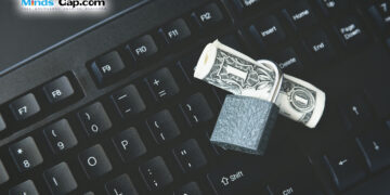 A high angle shot of a lock around a dollar bill on a black laptop